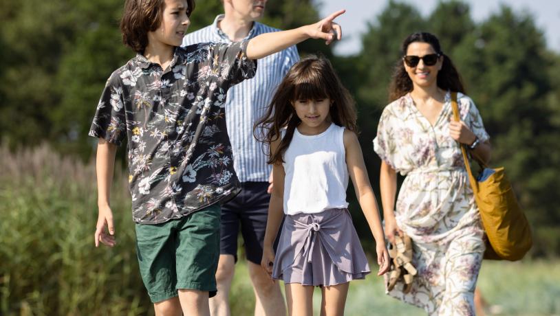 Familie med far mor og to børn går ved strand ved Odder 