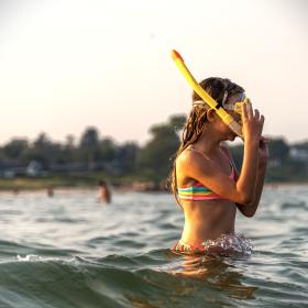 girl with diving glasses and a snorkel in the water at a Danish Beach